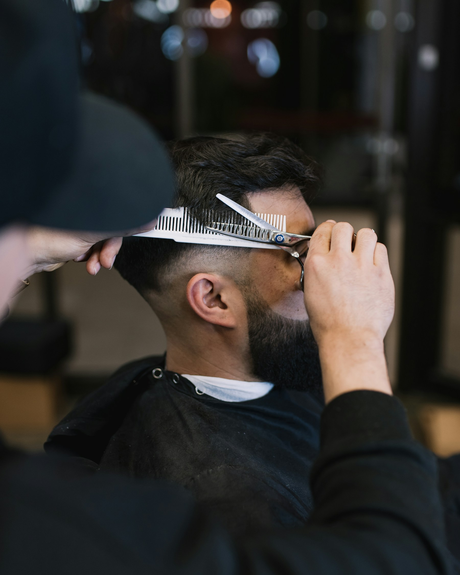Barber shaping a clean fade with scissors